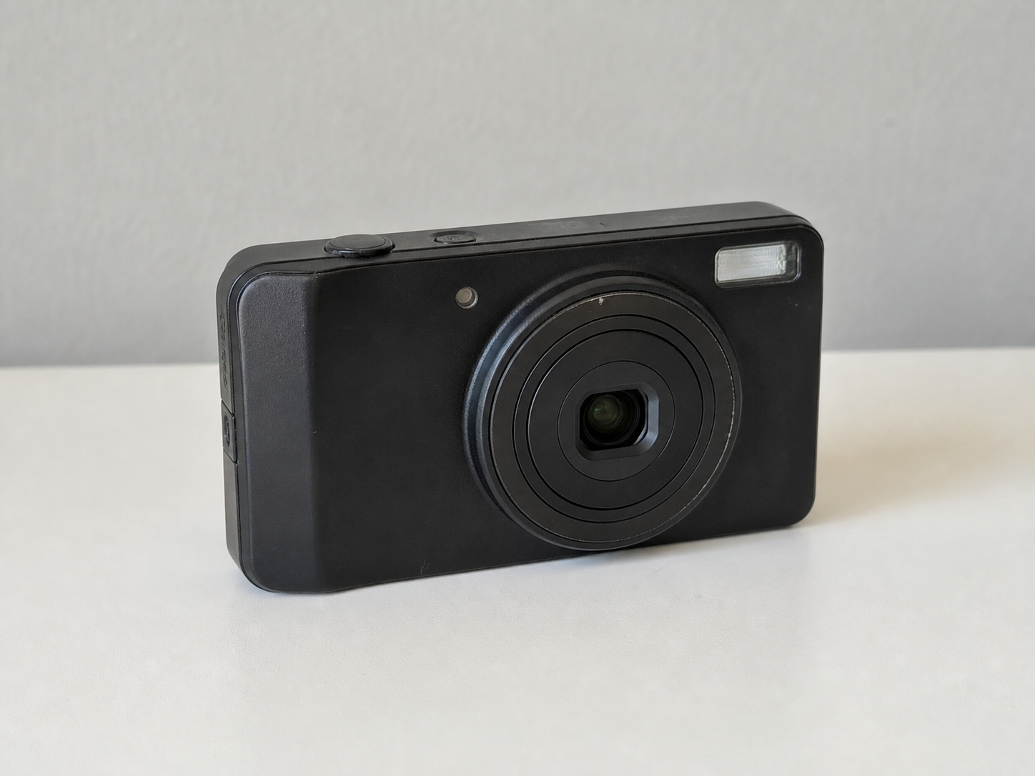Used black compact camera photographed on a white table